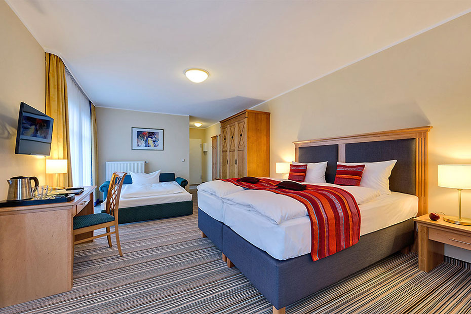 Hotelzimmer mit Doppelbett und Aufbettung
